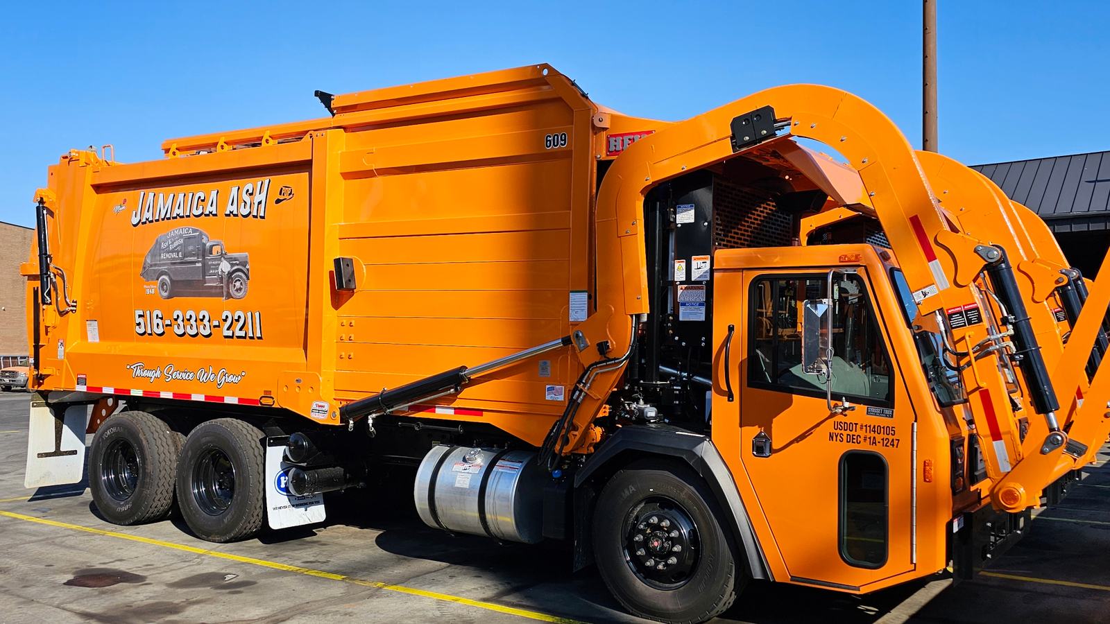 Jamaica Ash orange front-loader truck #609 — Through Service We Grow